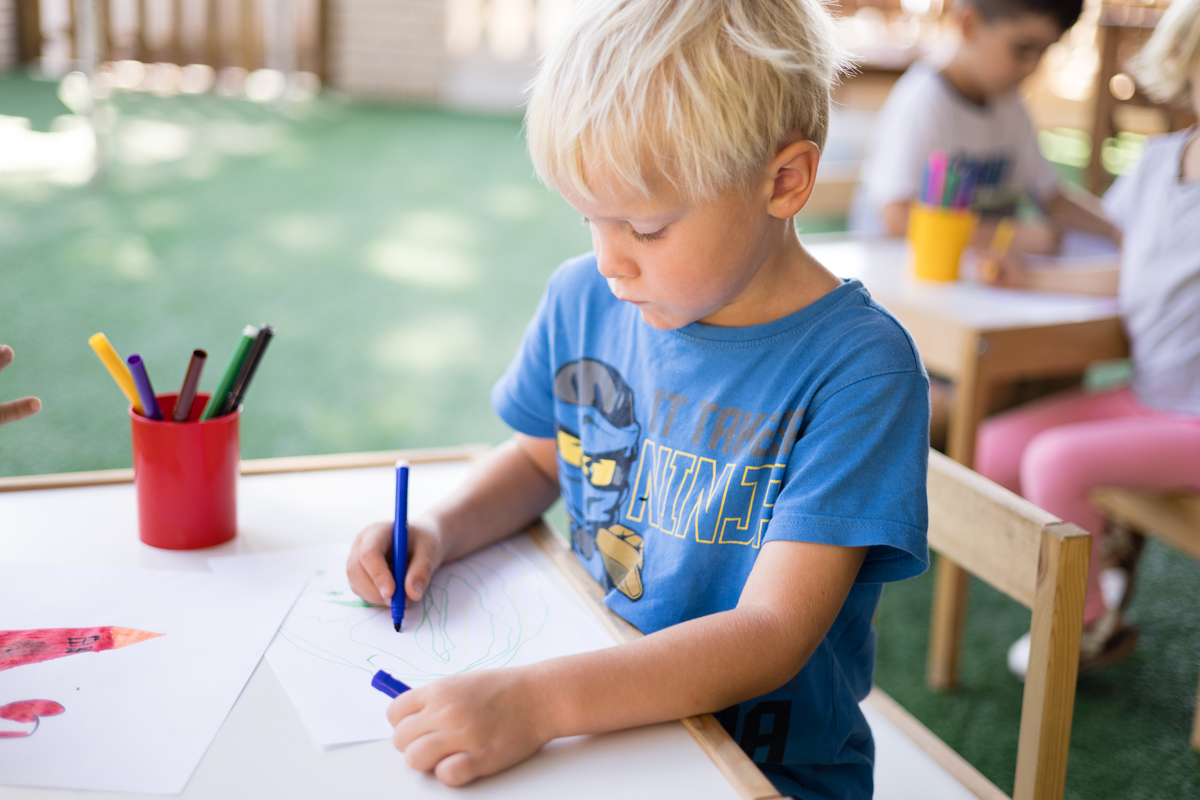 Un niño dibuja con lápices de colores